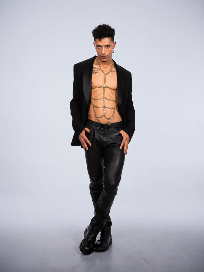 man die pak aan heeft met een vergulden bodychain harnas