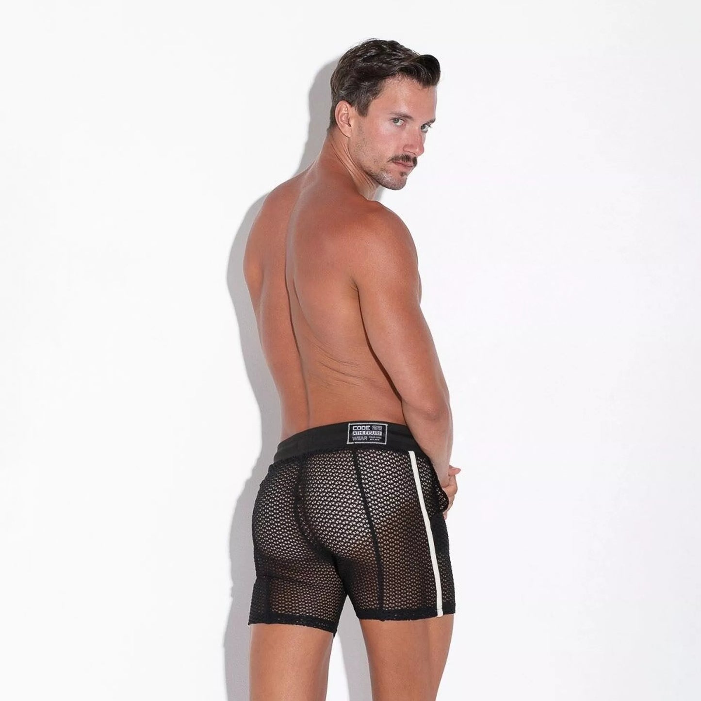 achterkant van man met fishnet shorts met aan de zijkant een witte streeo