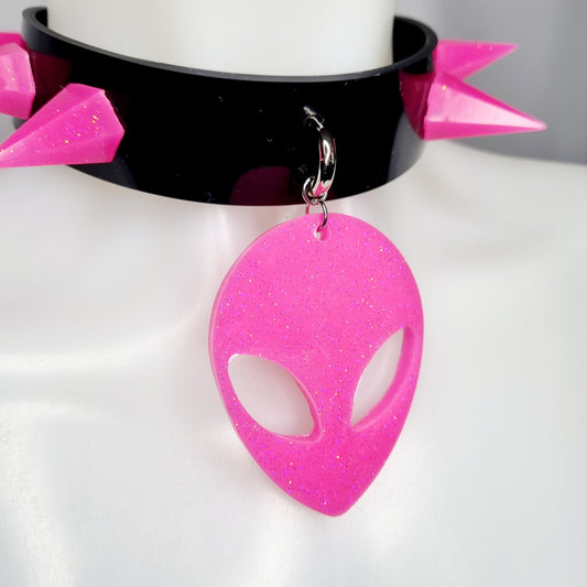 zijkant van zwarte siliconen choker met roze spikes en roze glitter alien hoofd