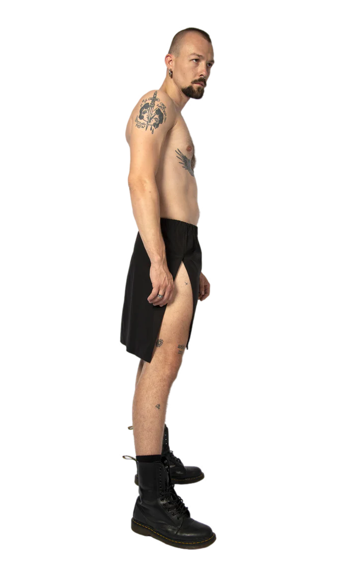zijkant van man met zwarte rok met twee splitten, techno outfit