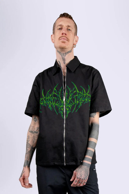 man met zwarte blouse met groene tribal, techno outfit