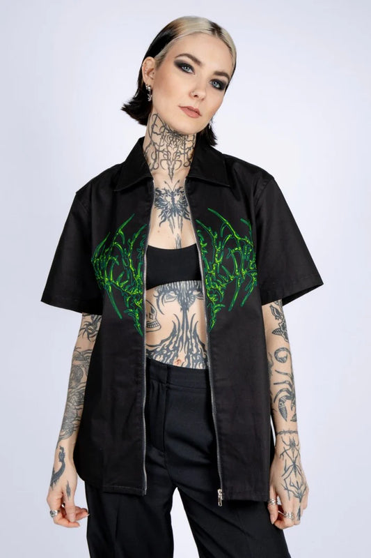 vrouw met opengeritste blouse met groene tribal, techno outfit