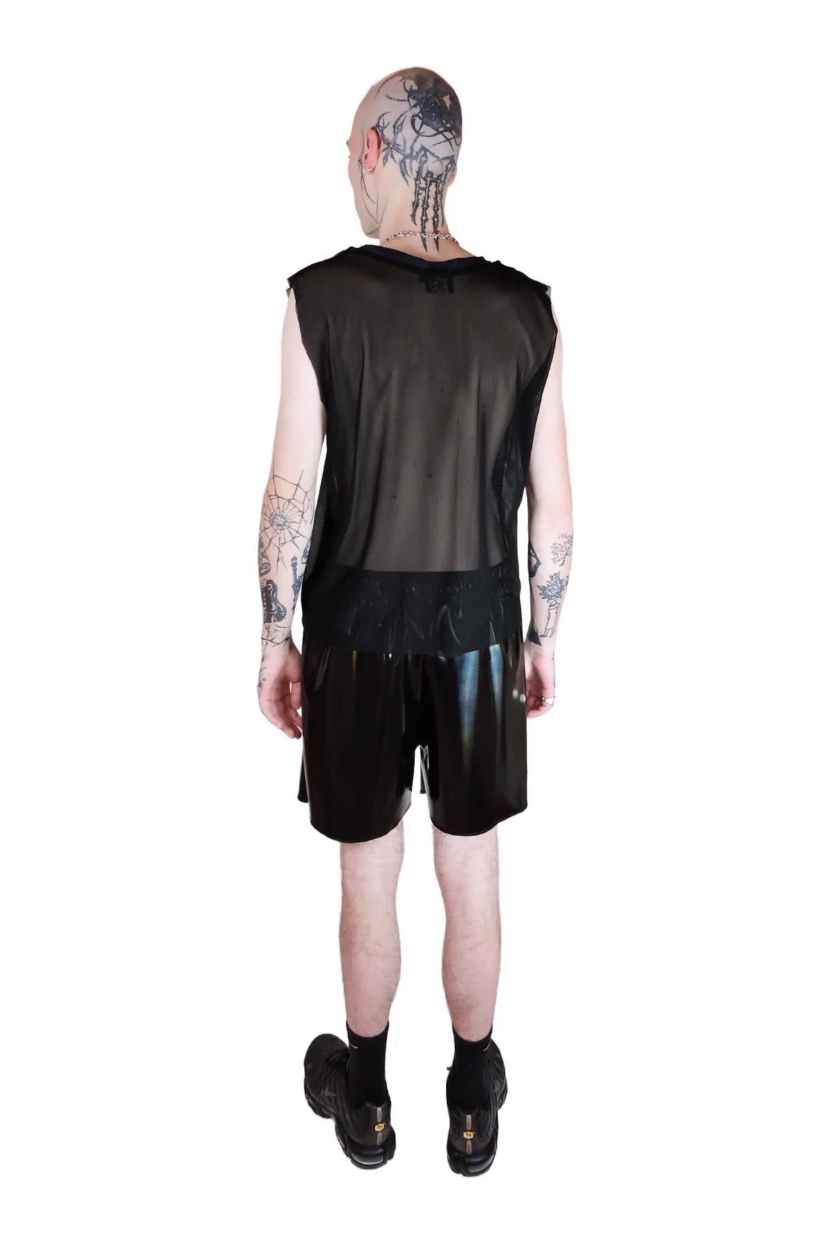 achterkant van kale jongen met zwarte fishnet shirt and zwarte oliekleurige shorts